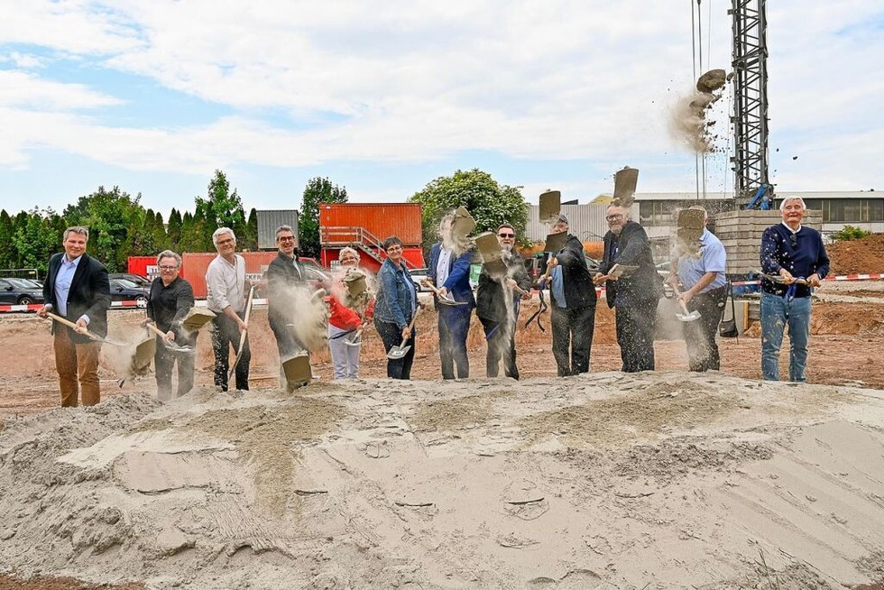 Foto von mehreren Personen, die mit Spaten Sand schaufeln